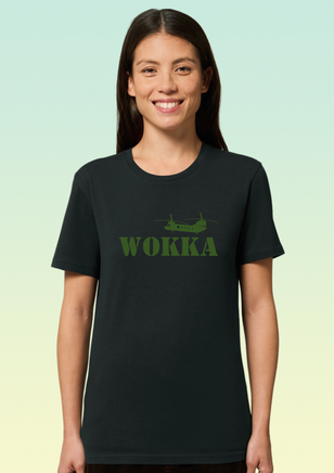A woman wearing a black organic cotton women’s t-shirt with khaki print featuring a stylised Chinook helicopter above bold text reading WOKKA.