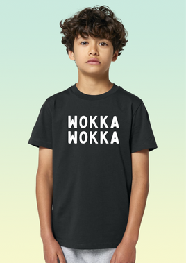 A boy wearing a black children’s t-shirt in organic cotton featuring white WOKKA WOKKA text printed across the chest.